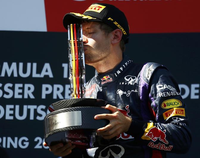 Vettel sul podio d un bacio al trofeo con i tre colori della bandiera della Germania. Reuters